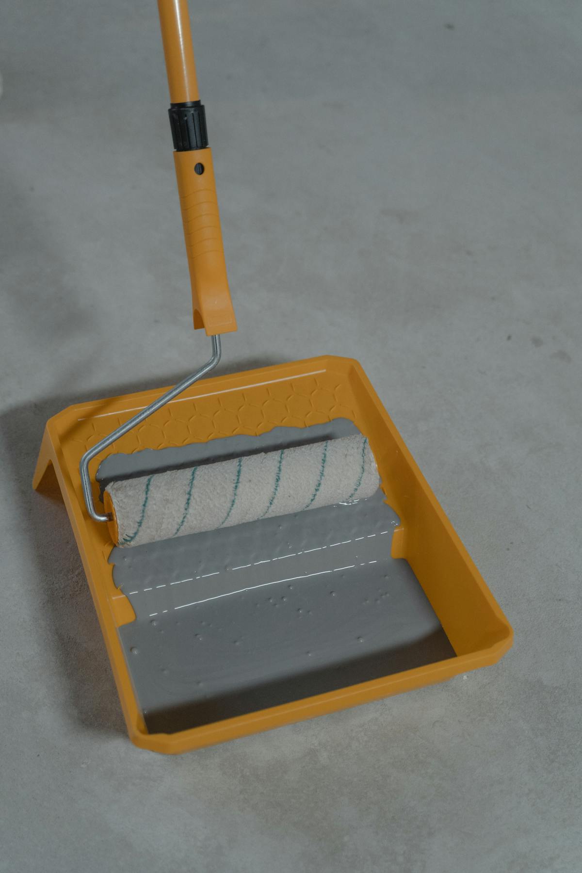 Paint roller and tray ready for a DIY epoxy kit application on a garage floor
