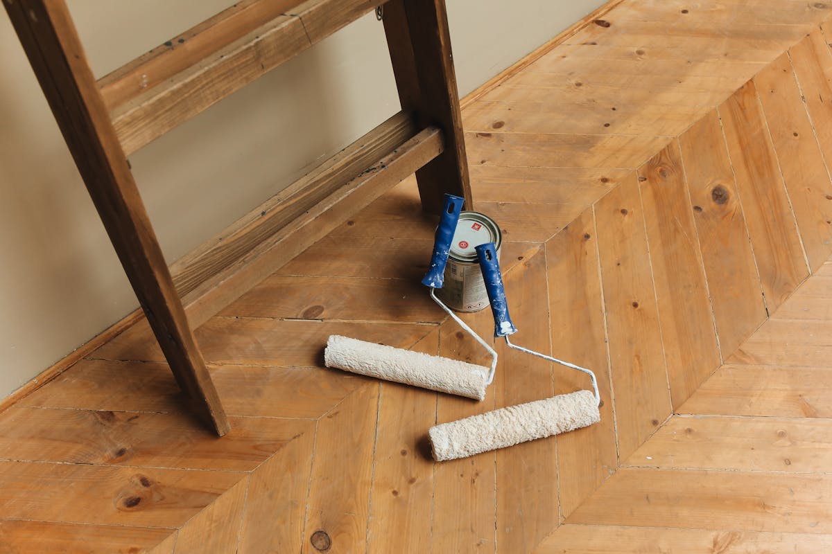 Paint rollers and DIY painting tools laid out on a floor for an epoxy coating job